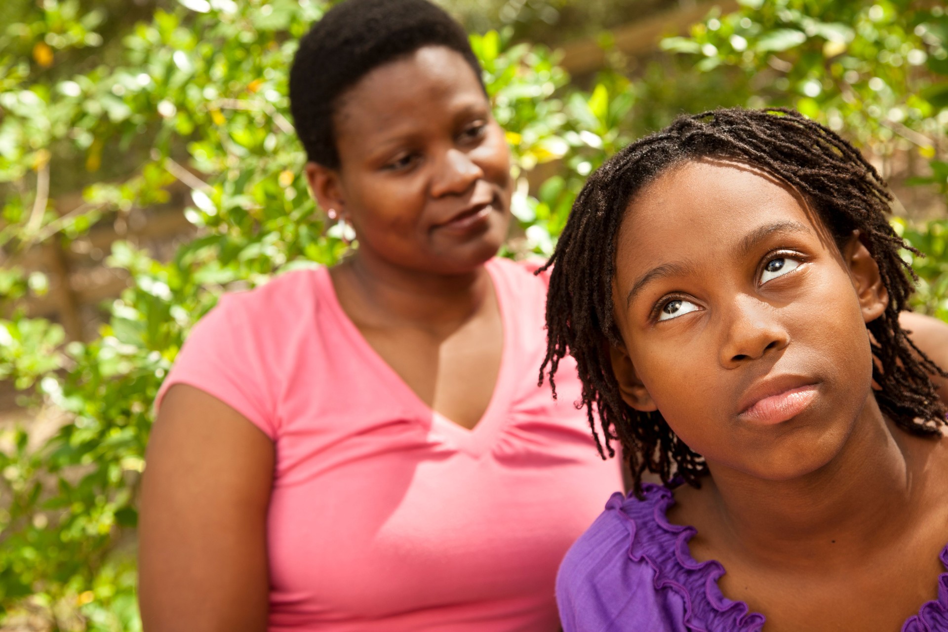 African descent mother talking with teenage daughter. Rolling her eyes.